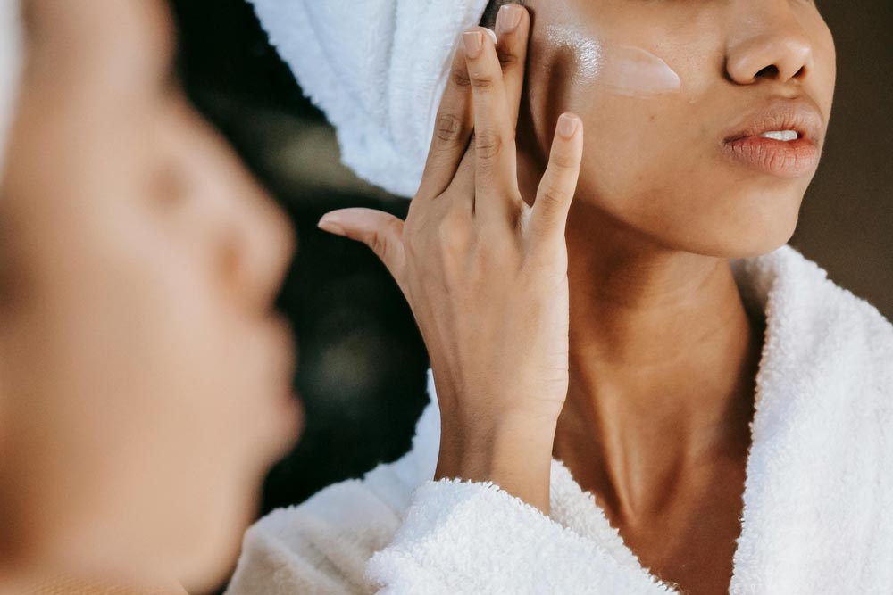 Woman applying moisturiser at home after a radiotherapy session